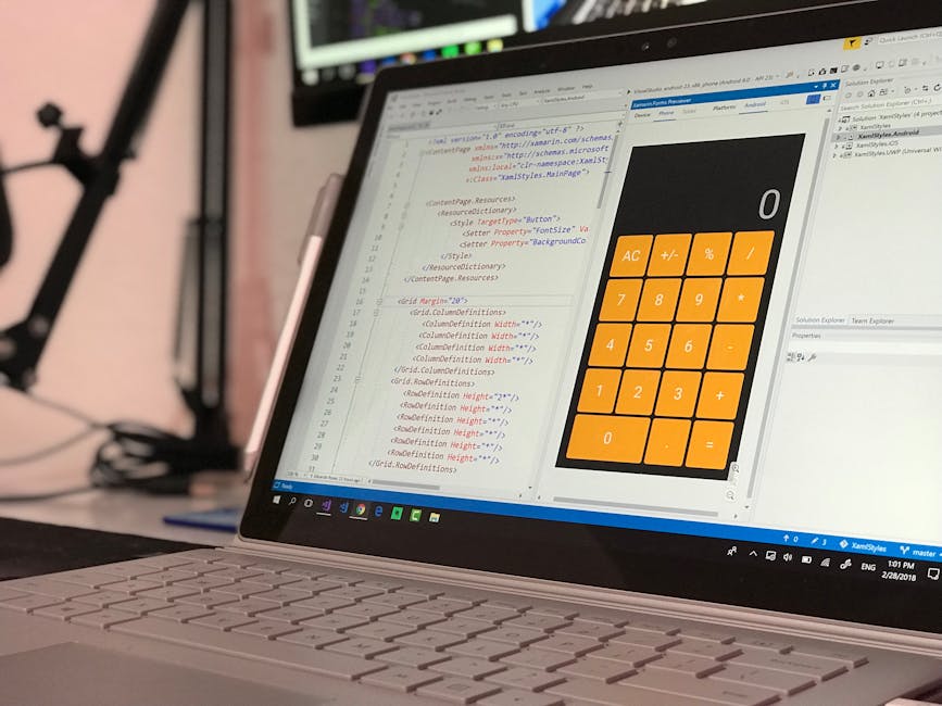 A laptop computer displaying a coding editor on the left side of the screen and a calculator application with orange buttons on the right side, set on a desk in an indoor workspace. The coding editor